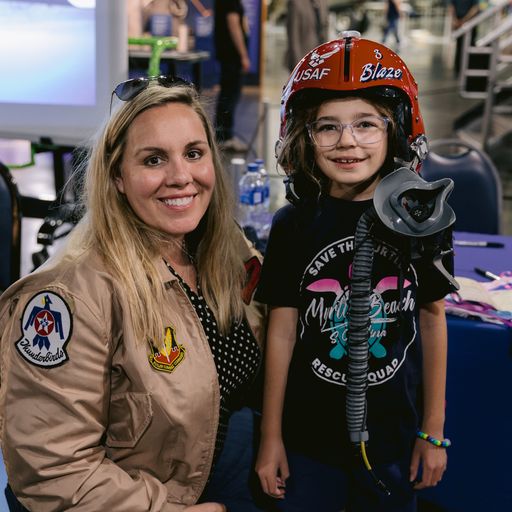 Woman Pilot and Child posing for picture with flight helmet
